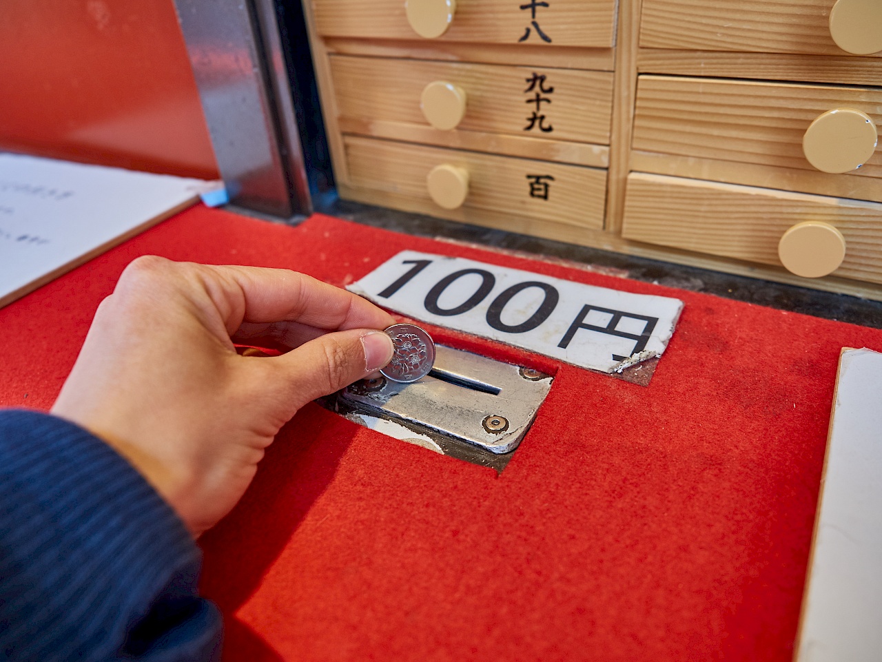 100 yen für ein omikuji im Senso-ji-Tempel in Tokyo zahlen